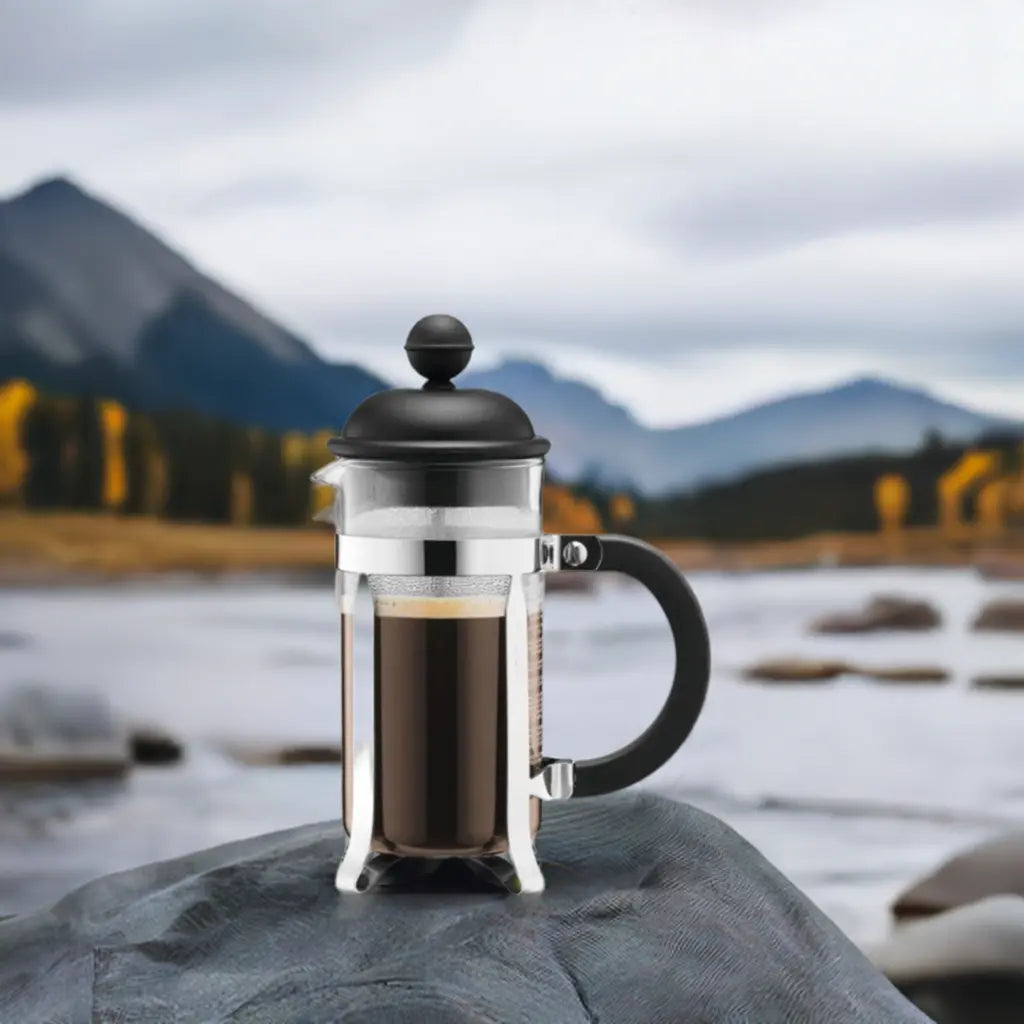 Brew-itCafe French press coffee maker placed on a rock with scenic mountains in the background