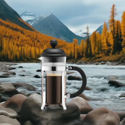 Brew-itCafe French press coffee maker placed on rocks by a serene river surrounded by autumn mountains